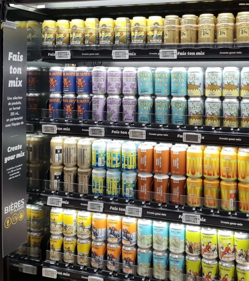 Le réfrigérateur Fais ton mix dans un IGA : cinq tablettes de canettes de microbrasseries, avec l'affiche de l'offre sur le côté