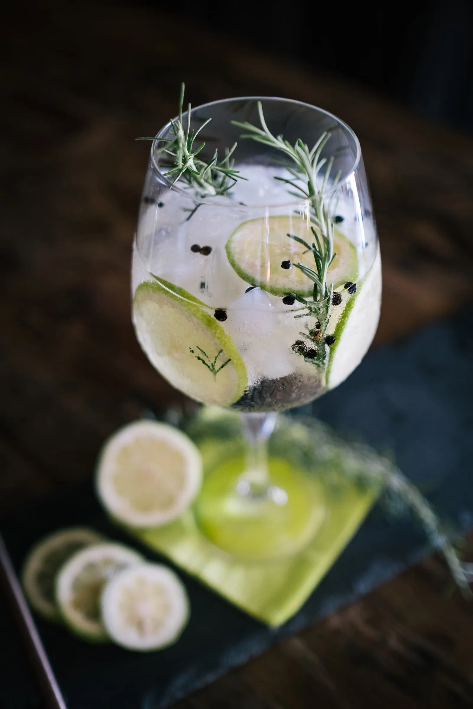 Élégant cocktail gin tonic garni de citron et de romarin, parfait pour une boisson rafraîchissante en été.