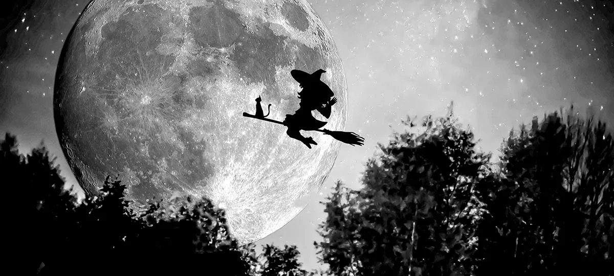 La silhopuette d'une sorcière volant deavnt la plaine lune sur un balais avec son chat