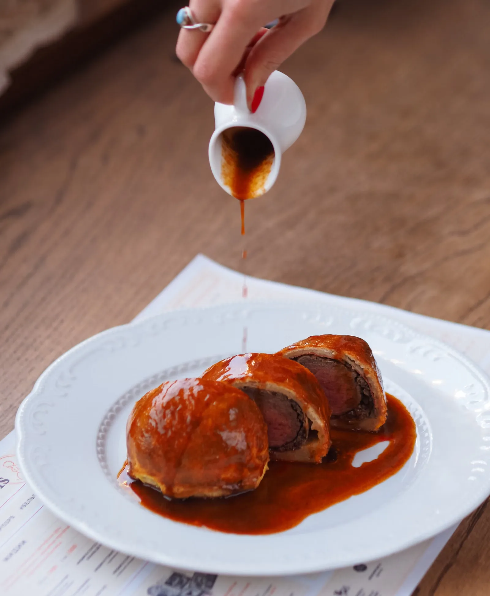 Gros plan sur un beef Wellington avec de la sauce versée, un plat gourmet délicieux.