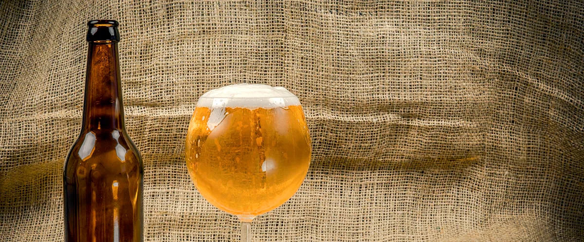 Verre de bière sur une table de bois à côté d'une bouteille