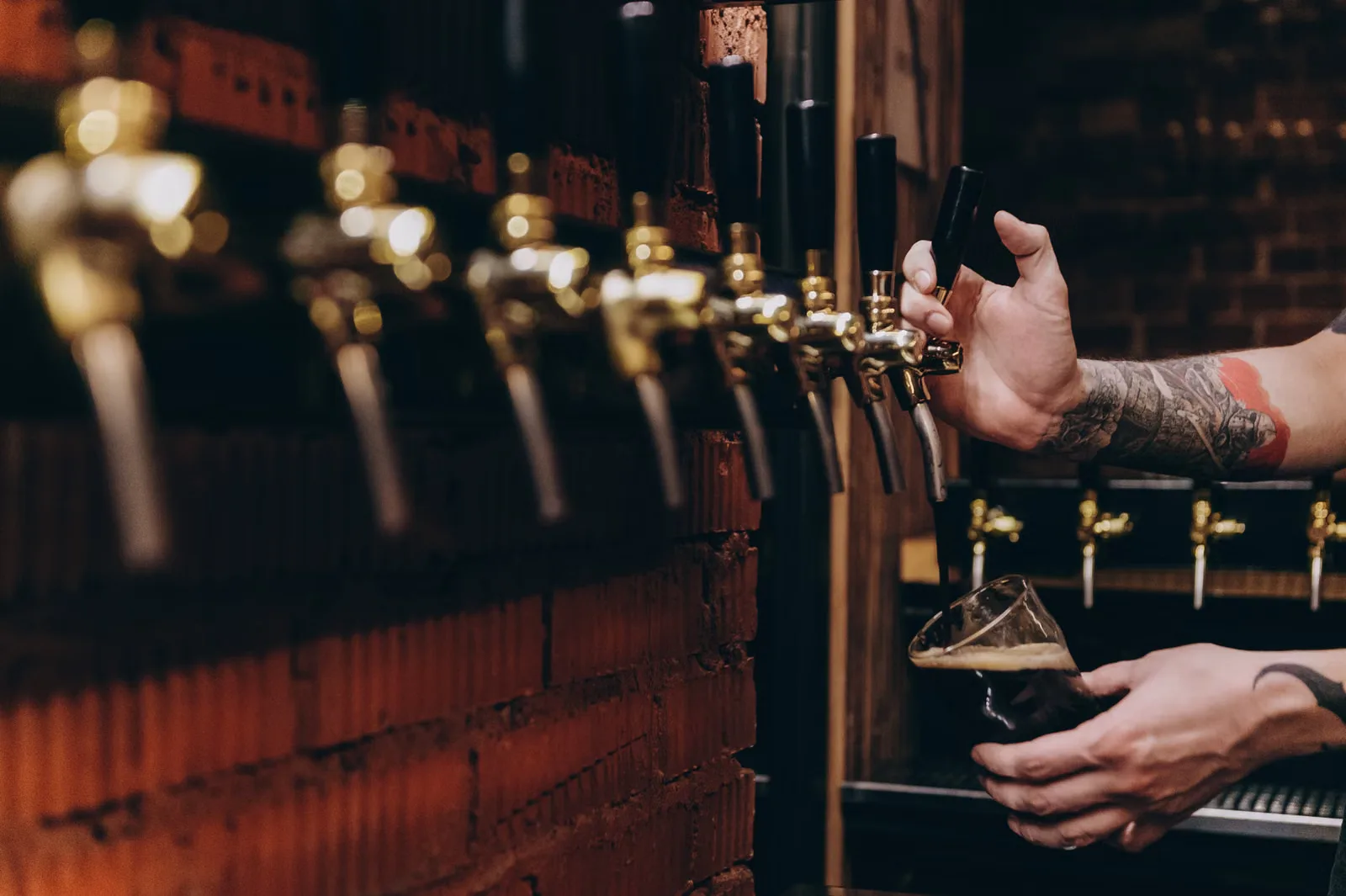 Gros plan sur une bière versée d'un robinet dans un verre dans un cadre de pub rustique.