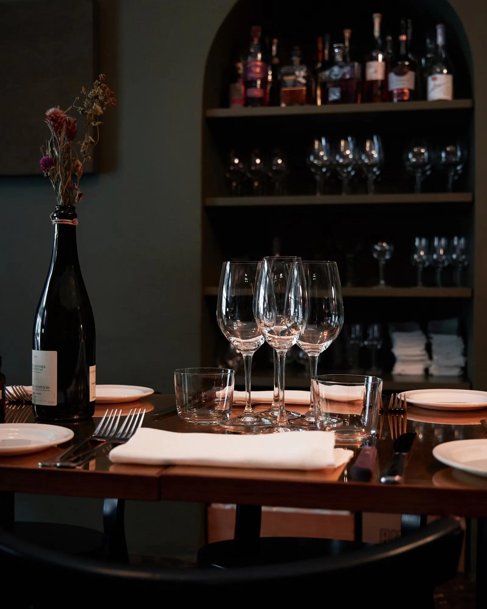 Mise en place sophistiquée avec des verres à vin dans une ambiance intime et chaleureuse.