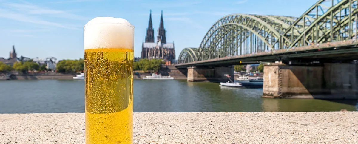 Verre de bière (kolch) sur le Rhin avec pont hohenzollern et cathédrale en Cologne.
