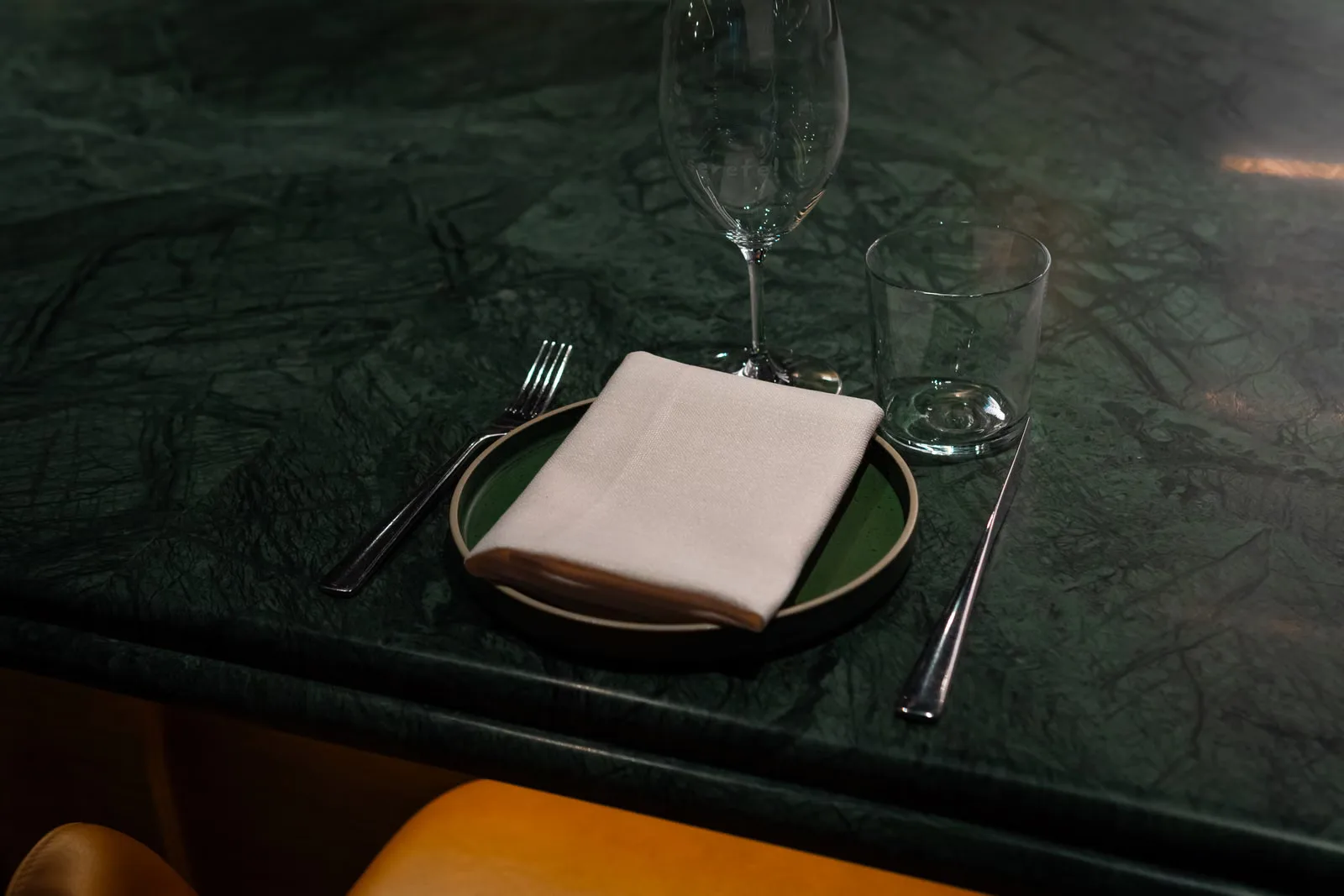 Une table élégamment dressée avec une serviette, une fourchette et des verres sur un comptoir en marbre vert.
