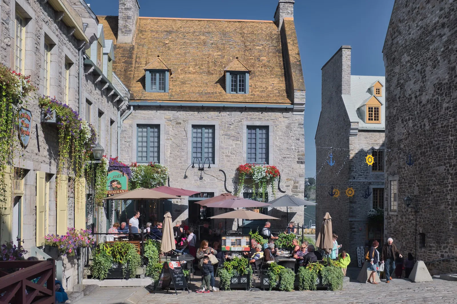 Café animé en terrasse sur une rue historique du Vieux-Québec, idéal pour profiter de l'été.